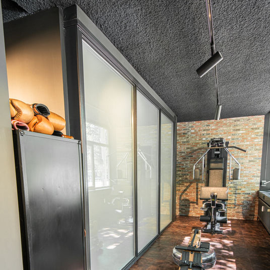 Donker akoestisch spuitplafond in zakelijke ruimte met industriële uitstraling